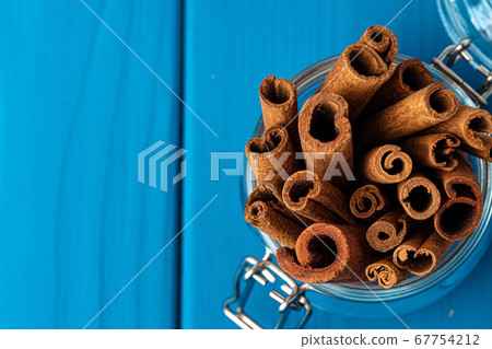 Cinnamon sticks in glass jar on blue wooden table 67754212
