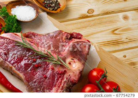 Raw t-bone meat with fresh vegetables and rosemary on the table Raw t-bone meat with fresh vegetables and rosemary on the table 67754279