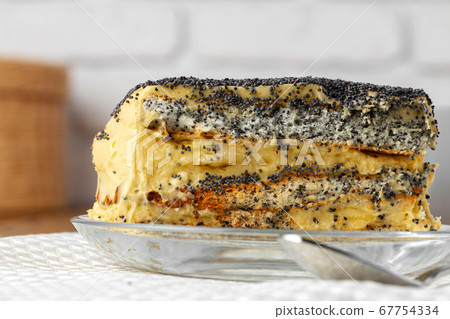 Piece of cake with poppy seeds on glass plate close up 67754334
