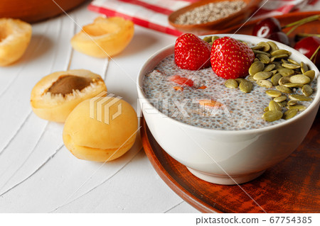 Chia pudding with strawberry and pumpkin seeds on wooden table 67754385