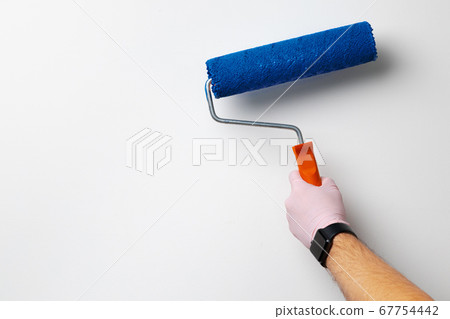 Gloved male hand painting wall into classic blue color 67754442