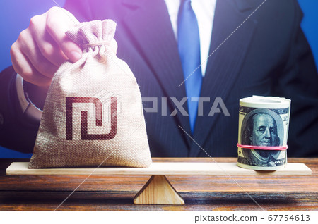 A man puts Israeli shekel money bag on the scales opposite to the dollar. Investments in foreign currency bonds. Protecting savings from inflation. Exchange rate, comparison of economic indicators. A man puts Israeli shekel money bag on the scales opposite to the dollar. Investments in foreign currency bonds. Protecting savings from inflation. Exchange rate, comparison of economic indicators. 67754613