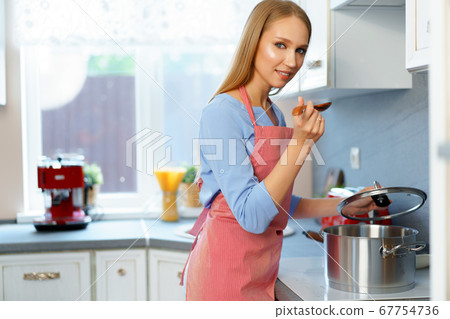 Attractive young blonde woman checking cooked food 67754736