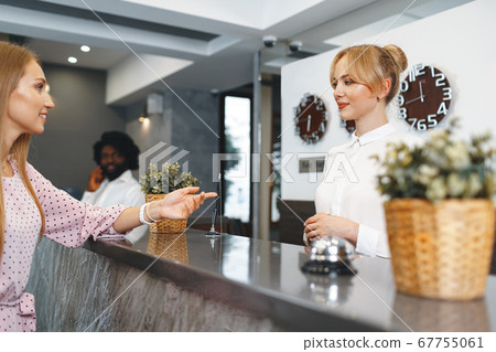 Blonde woman hotel guest checking-in at front desk in hotel 67755061