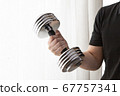 A man doing muscle training in his home room using dumbbells A man doing muscle training in his home room using dumbbells 67757341