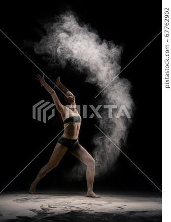 Slim female dancer throwing dust in air 67762902