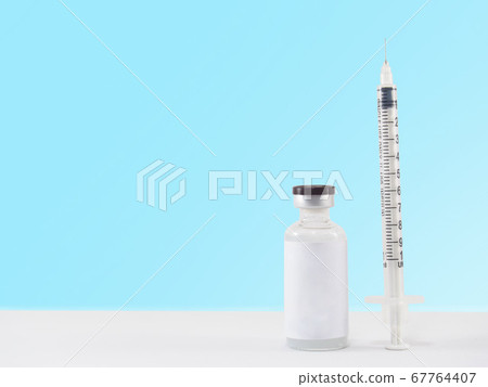 Blank label medical glass vial and plastic syringe for injection on white table with blue gradient background. Concept of vaccination, diabetes and cosmetic injection. Copy space. Blank label medical glass vial and plastic syringe for injection on white table with blue gradient background. Concept of vaccination, diabetes and cosmetic injection. Copy space. 67764407
