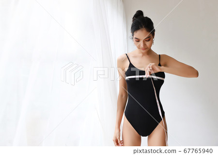 healthy and slim woman taking measurements of her breast 67765940