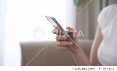 Woman operating a smartphone at home 67767485