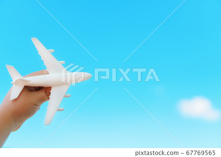 A white airplane in a child's hand against a blue 67769565