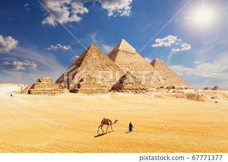 Famous Pyramids of Egypt and a bedouin with a camel, Giza, Cairo 67771377