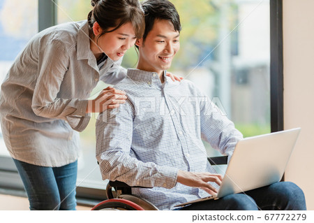 幾個男人和女人坐在輪椅上操作一台個人計算機 幾個男人和女人坐在輪椅上操作一台個人計算機 67772279
