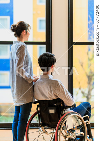 Man and woman couple in wheelchair looking out Man and woman couple in wheelchair looking out 67772400