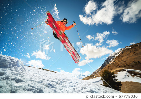 Jump with a trick in the ozdou athlete skier with a kicker on a sunny day of spring or winter against the blue sky and sun 67778036