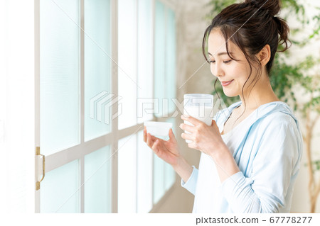 Young woman standing on the windowsill with protein 67778277