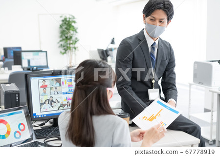 兩個戴著面具的上班族在與變焦交談時在室內談話 兩個戴著面具的上班族在與變焦交談時在室內談話 67778919