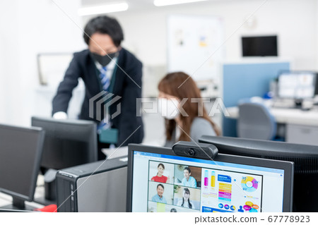 兩個辦公室工作人員與網絡會議的網絡攝像頭和那邊的面具 兩個辦公室工作人員與網絡會議的網絡攝像頭和那邊的面具 67778923