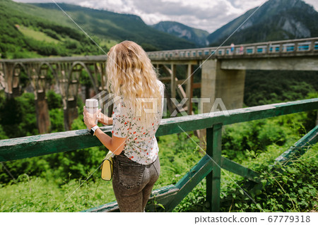 woman traveller holding coffee mug with mountains view 67779318