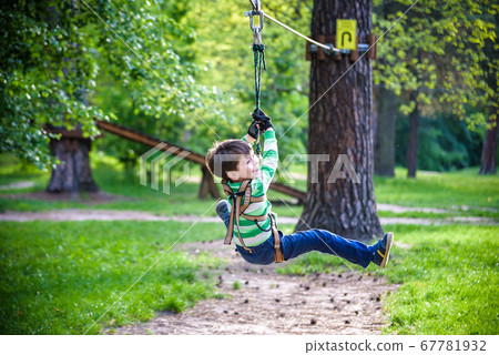 smiling boy rides a zip line. happy child on the smiling boy rides a zip line. happy child on the 67781932