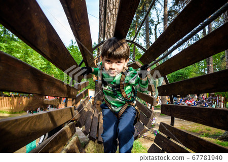 Little boy playing at rope adventure park. Summer Little boy playing at rope adventure park. Summer 67781940