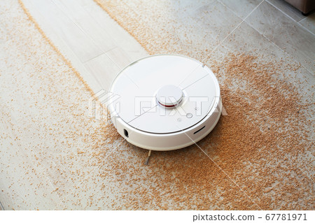 Smart House. Vacuum cleaner robot runs on wood floor in a living room 67781971