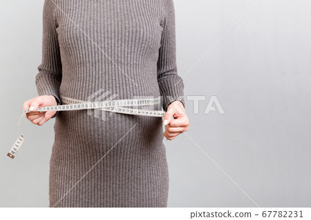Close up of pregnant woman in gray dress measuring Close up of pregnant woman in gray dress measuring 67782231