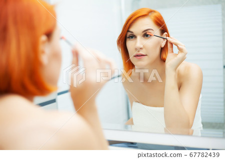 Pretty girl use care product in a bright bathroom. Pretty girl use care product in a bright bathroom. 67782439