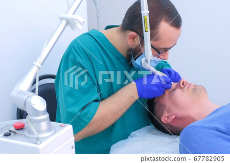 Surgeon removes papillomas on eyelid for man with laser in clinic surgical cure. 67782905