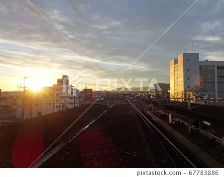 從車站的高架橋上欣賞早晨的陽光，鐵軌，月台屋頂和周圍的城市 67783886