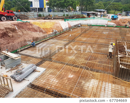 KUALA LUMPUR, MALAYSIA -MARCH 3, 2020: Building floor slab under construction. Construction workers fabricating the timber formwork and installing the steel reinforcement bar. KUALA LUMPUR, MALAYSIA -MARCH 3, 2020: Building floor slab under construction. Construction workers fabricating the timber formwork and installing the steel reinforcement bar. 67784669