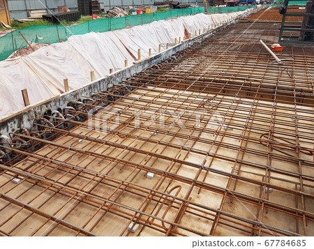 KUALA LUMPUR, MALAYSIA -MARCH 3, 2020: Building floor slab under construction. Construction workers fabricating the timber formwork and installing the steel reinforcement bar. KUALA LUMPUR, MALAYSIA -MARCH 3, 2020: Building floor slab under construction. Construction workers fabricating the timber formwork and installing the steel reinforcement bar. 67784685