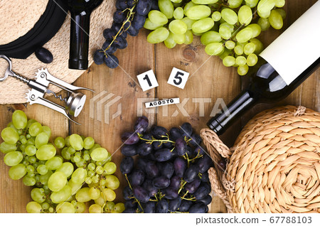 Grapes, bottle of wine, glass with wine, hat on a wooden background. View from above. Winemaking 67788103