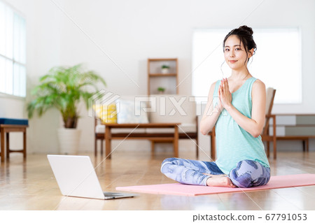 Young woman enjoying online yoga in the living room at home 67791053