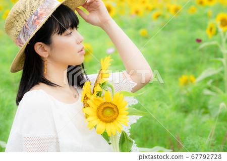 A woman in a sunflower field and a white dress 67792728