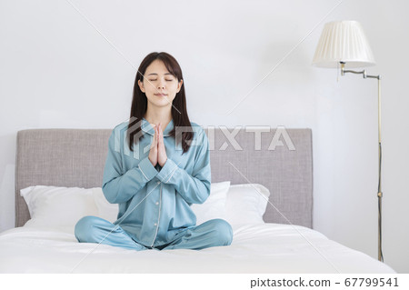 Young woman meditating in pajamas on the bed Morning yoga image Young woman meditating in pajamas on the bed Morning yoga image 67799541