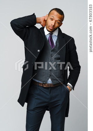 studio shot of a african-american businessman wearing coat over light grey background 67803583