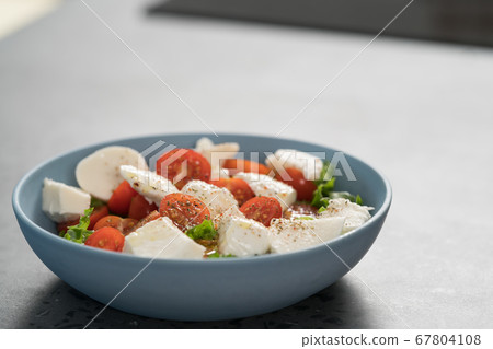 salad with mozzarella, tomatoes and lettuce in blue bowl salad with mozzarella, tomatoes and lettuce in blue bowl 67804108