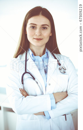 Doctor woman standing straight with arms crossed, portrait. Perfect medical service in clinic. Medicine and healthcare concepts Doctor woman standing straight with arms crossed, portrait. Perfect medical service in clinic. Medicine and healthcare concepts 67809219