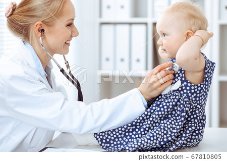 Doctor and patient in hospital. Little girl dressed in dark blue dress in peas is being examined by doctor with stethoscope. Medicine concept Doctor and patient in hospital. Little girl dressed in dark blue dress in peas is being examined by doctor with stethoscope. Medicine concept 67810805