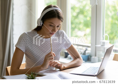 Focused girl in headphones study on laptop at home 67811639