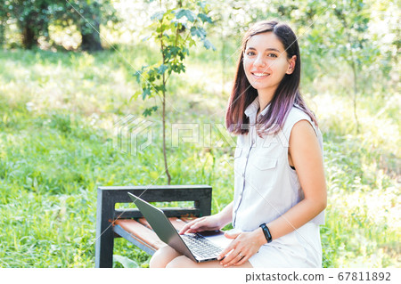 cheerful young student learning remotely on laptop in park keeping social distance and enjoying time alone cheerful young student learning remotely on laptop in park keeping social distance and enjoying time alone 67811892