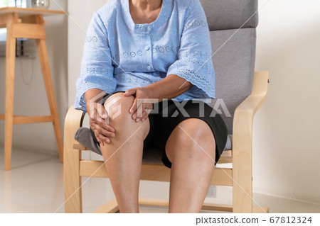 senior woman suffering from knee pain at home, health problem concept 67812324