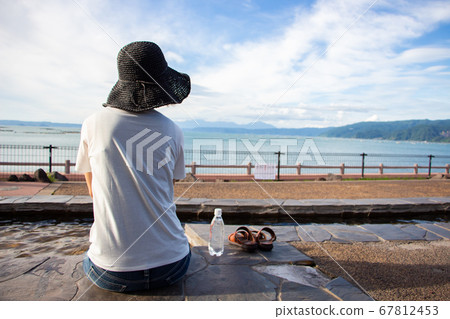 A woman in a white shirt entering a long footbath at Yusurikan, a roadside station in Tarumi City, Kagoshima Prefecture. A woman in a white shirt entering a long footbath at Yusurikan, a roadside station in Tarumi City, Kagoshima Prefecture. 67812453