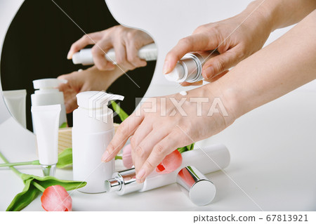 Hand applying natural skincare, Cosmetic bottle containers packaging with tulip flower essence Hand applying natural skincare, Cosmetic bottle containers packaging with tulip flower essence 67813921