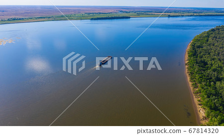 A barge or dry cargo ship goes upstream of the Volga River near Astrakhan. Aerial photography 67814320