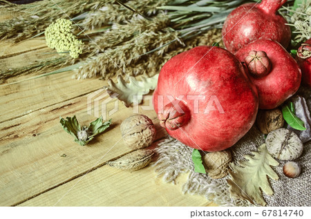 Fruits of pomegranates,wildflowers with nuts on a coarse napkin lying on wooden boards 67814740
