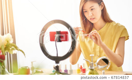 介紹在智能手機照相機前面的一個少婦化妝用品 介紹在智能手機照相機前面的一個少婦化妝用品 67814837