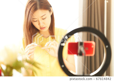 A young woman introducing cosmetics in front of a smartphone camera 67814842