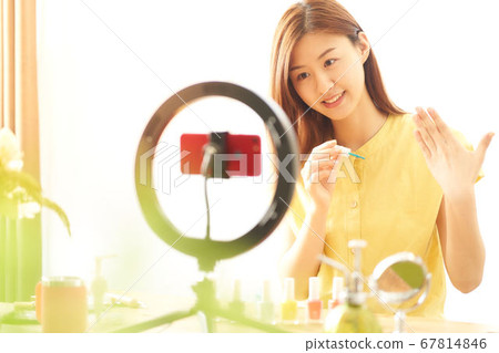 A young woman introducing cosmetics in front of a smartphone camera 67814846