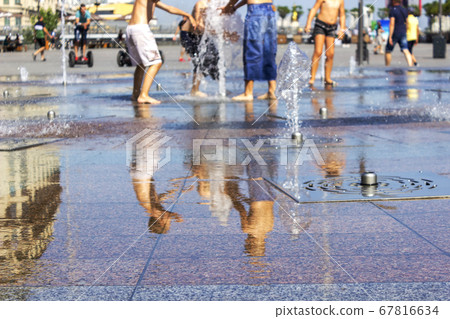 Children splashing in the city fountain. Hot summer day. 67816634